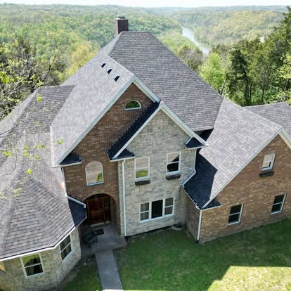 Completed architectural shingle roof on a large stone and brick home